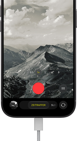 iPhone 18 Pro, Vorderseite, das Display zeigt eine Berglandschaft, mit der Kamera Modus Überlagerung im Zeitraffer Modus, mit dem Netzkabel am Ladeanschluss